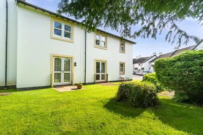 a white house with a lawn in front of it at Quaver Cottage in Keswick