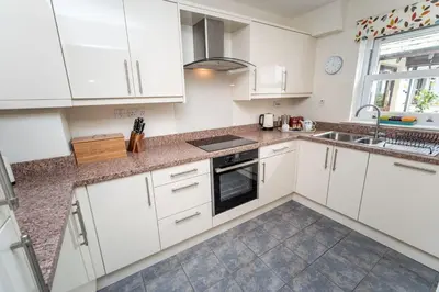 a kitchen with white cabinets and a sink and a window at Quaver Cottage in Keswick