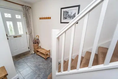 a staircase in a home with white walls and a white door at Quaver Cottage in Keswick