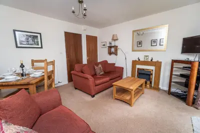 a living room with a red couch and a fireplace at Quaver Cottage in Keswick