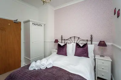 a bedroom with a bed with purple and white pillows at Bridge Cottage in Keswick