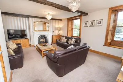 a living room with leather furniture and a fireplace at Bridge House in Keswick