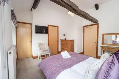 a bedroom with a large bed and a chair at Bridge House Apartment 3 in Keswick