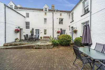 a patio with a table and chairs and a building at Bridge Mews in Keswick
