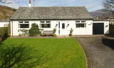 a white house with a bench in a yard at Causey View in Braithwaite