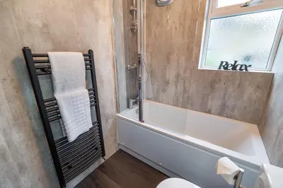 a bathroom with a tub and a toilet and a window at Byways in Keswick