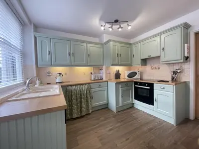 a kitchen with green cabinets and a sink at Birchgate in Keswick