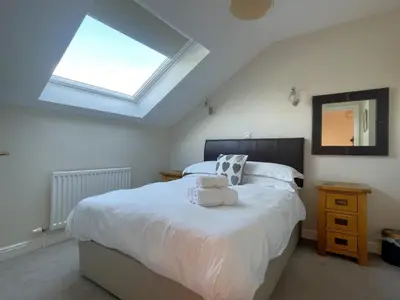 a bedroom with a large white bed with a skylight at Alison's View in Keswick