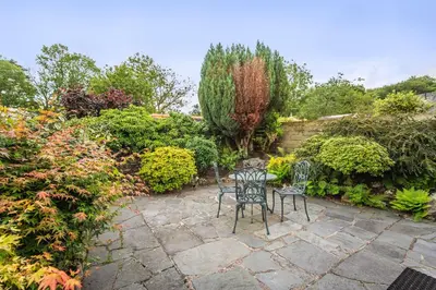a patio with two chairs and a table in a garden at Millside Cottage in Braithwaite