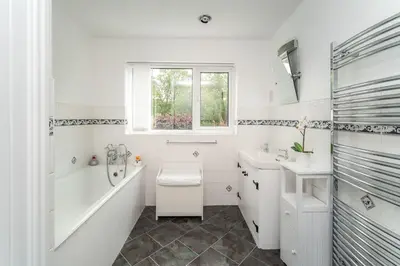 a white bathroom with a tub and a sink at Millside Cottage in Braithwaite