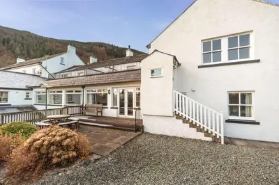 a white house with a porch and a patio at Lake View Cottage in Braithwaite