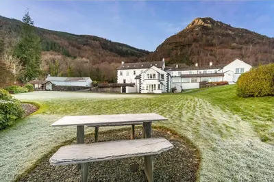 a bench sitting in the grass in front of a house at Lake View Cottage in Braithwaite