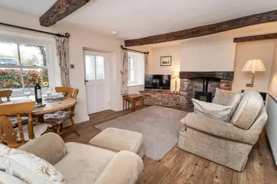 a living room with a table and chairs and a fireplace at Jasmine Cottage in Portinscale