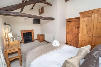 a bedroom with a bed and a fireplace at Jasmine Cottage in Portinscale