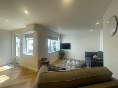 a living room with a couch and a clock on the wall at Daisy Cottage in Keswick