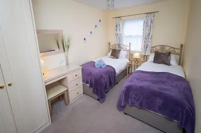 a bedroom with two beds and a desk and a mirror at Greta Bank in Keswick