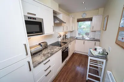 a kitchen with white cabinets and a counter top at Greta Bank in Keswick
