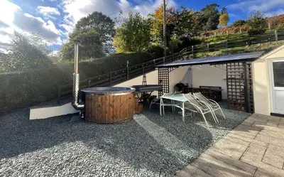 a patio with a barrel and a table and a grill at Rock Lynn in Braithwaite