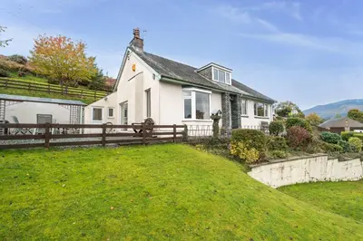 a white house with a fence and a yard at Rock Lynn in Braithwaite