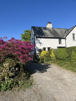 a white house with purple flowers in front of it at Rose Bank Cottage in Braithwaite