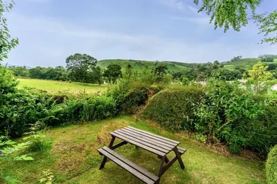 a wooden bench sitting on the grass in a field at Rose Bank Cottage in Braithwaite