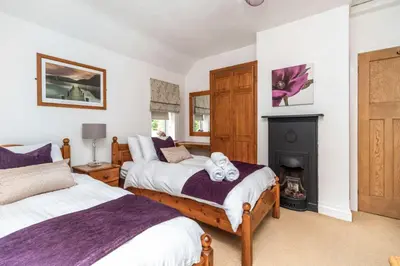 a bedroom with two beds and a fireplace at Rose Bank Cottage in Braithwaite