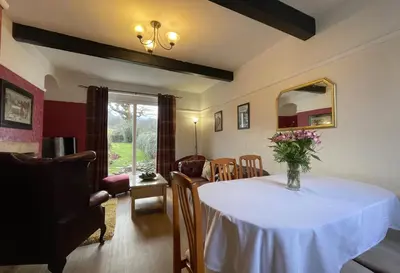 a living room with a table with a vase of flowers on it at Rose Bank Cottage in Braithwaite