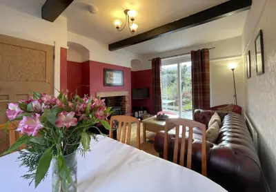 a living room with a table with a vase of flowers at Rose Bank Cottage in Braithwaite