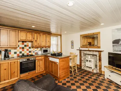 a kitchen with wooden cabinets and a fireplace at 2 Burnside Place in Kirkcudbright