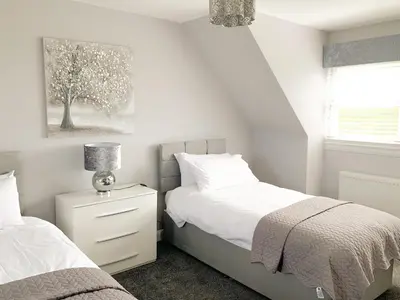 a white bedroom with two beds and a window at Float bay view in Stranraer