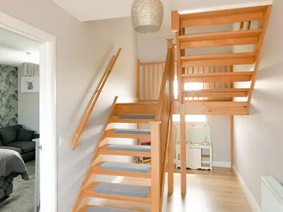 a wooden staircase in a living room with white walls at Float bay view in Stranraer