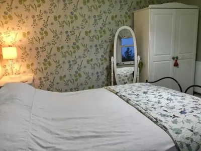 a bedroom with a bed and a mirror and a chair at The Glen Mona Hotel in Maughold