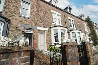 a brick house with white doors and a fence at Shields in Keswick