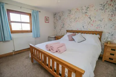 a bedroom with a bed with pink towels on it at Bramblewood Cottage in Crookdake