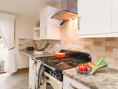 a kitchen with a stove and a bowl of vegetables at Bramblewood Cottage in Crookdake