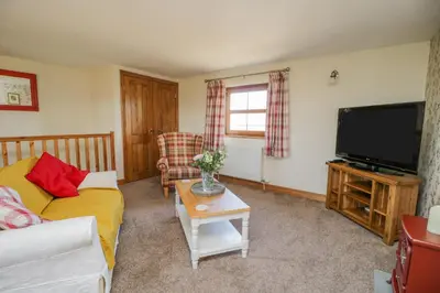 a living room with a couch and a flat screen tv at Bramblewood Cottage in Crookdake