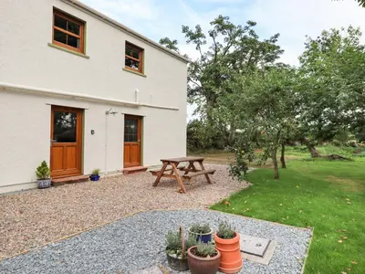 a patio with a picnic table in front of a house at Bramblewood Cottage in Crookdake