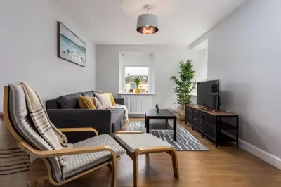 a living room with a couch and a tv at Shore View - Donnini Apartments in Prestwick