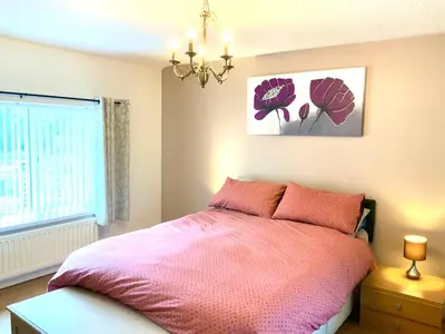 a bedroom with a pink bed and a chandelier at Parkside Mews in Frizington