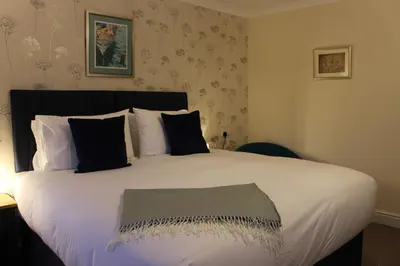 a bedroom with a large white bed with black pillows at Woodlands Country House & Cottage in Ireby