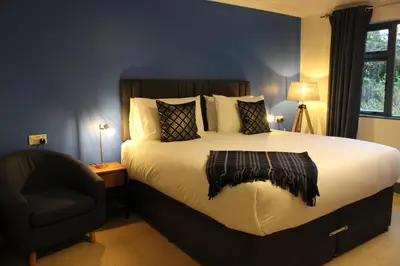 a bedroom with a large bed and a chair at Woodlands Country House & Cottage in Ireby