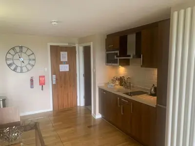 a kitchen with wooden cabinets and a clock on the wall at Ullswater Suite in Penrith