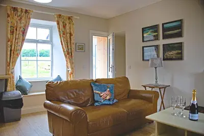 a living room with a brown leather couch and a window at Beachcombers in Dumfries