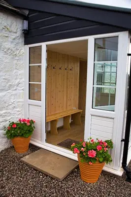 an open door with two potted plants and a bench at Beachcombers in Dumfries