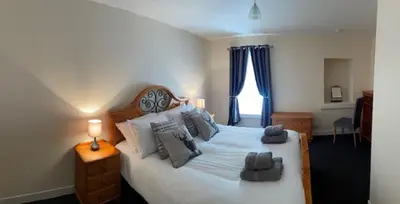 a bedroom with a large white bed with gray pillows at 1-2 Dialknowe Holiday Cottage - Wanlockhead in Wanlockhead