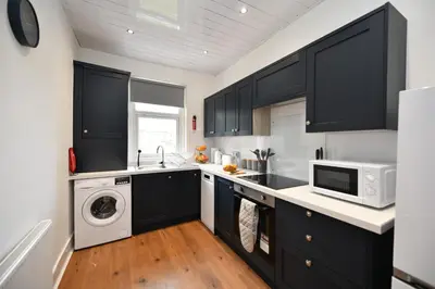a kitchen with black cabinets and a washer and dryer at Greensleeves Place in Troon