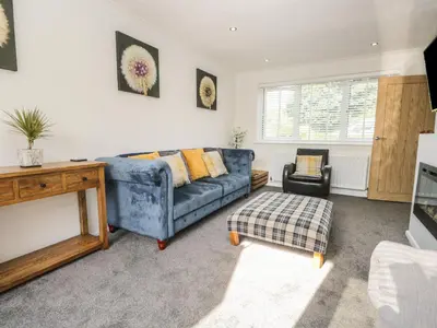 a living room with a blue couch and a tv at 26 Hycemoor Way in Millom