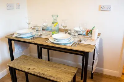 a wooden table with plates and glasses on it at Adrian House, near Hospital, easy parking + garden in Carlisle