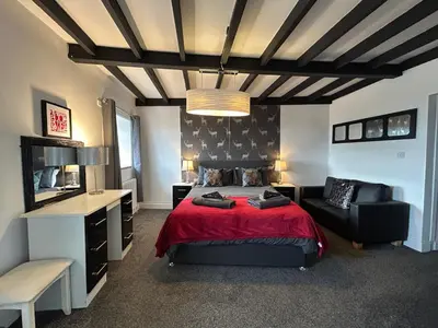a bedroom with a red bed and a black chair at Solway Firth View in Annan