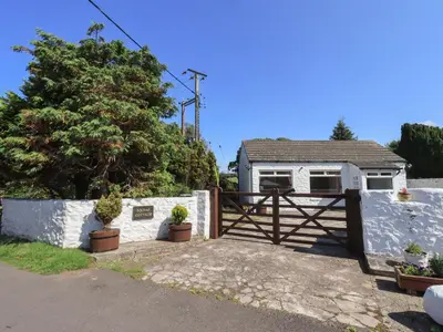 a white house with a gate and a fence at Solway Cottage in Annan
